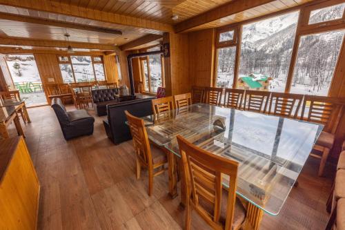 uma sala de jantar com uma mesa de vidro e cadeiras em Adventure Valley em Manali