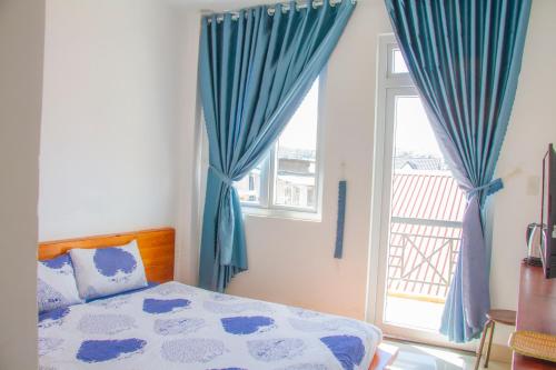 a bedroom with a bed and a window with blue curtains at Ha Khoa Hotel Dalat in Da Lat