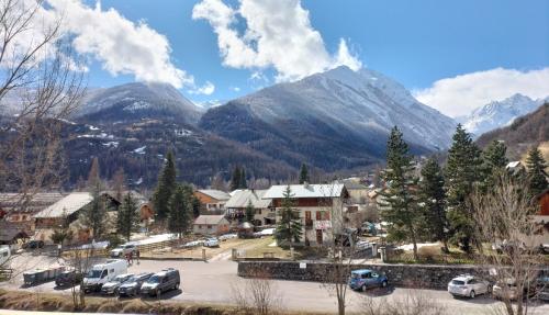 a town with cars parked in a parking lot in front of mountains at A découvrir joli petit Appart au coeur du village in Vallouise