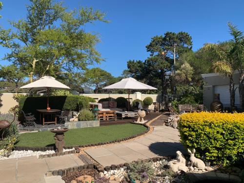 a garden with a patio with umbrellas and tables and chairs at Kaya La Provence in Cape Town