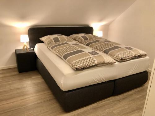 a bed with a black frame and pillows on it at Spacious apartment near ski-lift in NeuhÃ¼tten