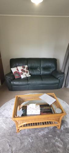 ein Wohnzimmer mit einem schwarzen Sofa und einem Couchtisch in der Unterkunft Couples Retreat in Reefton