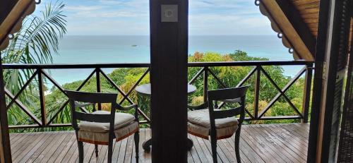 a balcony with two chairs and a view of the ocean at Mango Lodge in Anse Volbert Village
