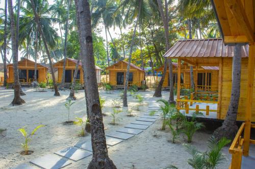 a group of houses on the beach with palm trees at The Pearl Beach Resort in Canacona