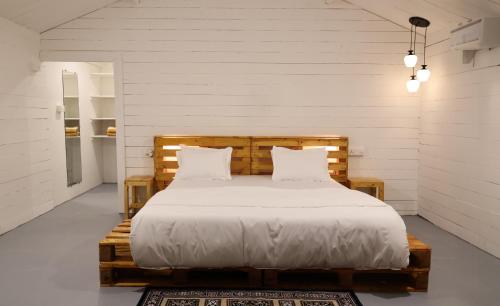 a bedroom with a wooden bed with white sheets and pillows at The Pearl Beach Resort in Canacona