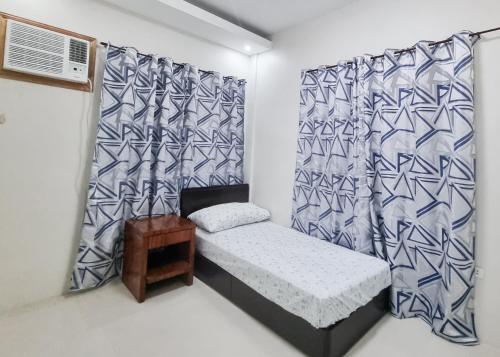 een kleine kamer met een bed en een gordijn bij Millenia Oaks Apartments 2 in Subic