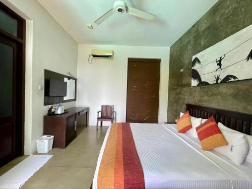 a bedroom with a bed with a ceiling fan at Olanro Hotel Negombo in Negombo