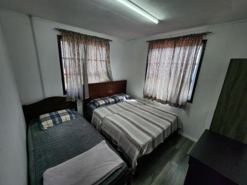 a small bedroom with two beds and two windows at Hillside Villa in Kampong Kundassan