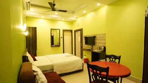 a hotel room with a bed and a table and a desk at Hotel Shantinivas - Tarapith in Tarapith