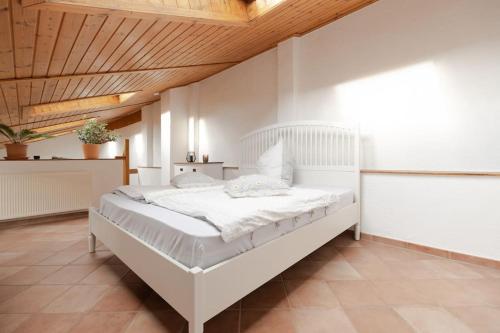 a white bed in a bedroom with a wooden ceiling at Helles Gästehaus in St. Johann in Sankt Johann