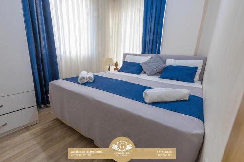 een groot bed met blauwe en witte kussens erop bij Gunduzler Deluxe Hotel - Antalya Center in Antalya