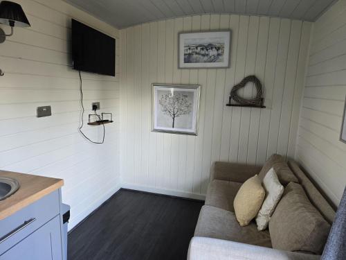 a living room with a couch and a television at Glamping Hut - Riverside 1 in Welshpool