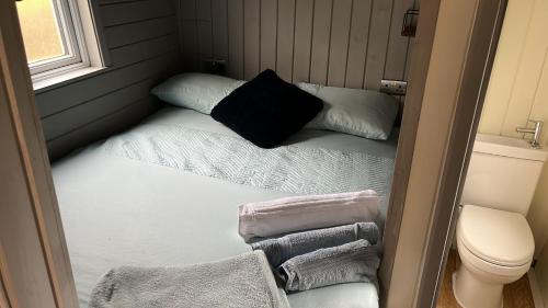 Habitación pequeña con cama y toallas. en Glamping Hut - Riverside 2, en Welshpool