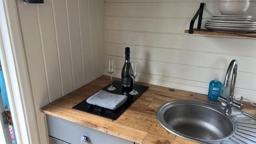 a kitchen counter with a sink and wine glasses at Shepherds Hut - Riverside 2 in Welshpool