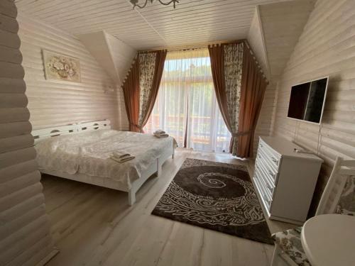 ein Schlafzimmer mit einem Bett und einem großen Fenster in der Unterkunft Oasis Karpat in Poljana