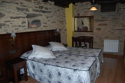 a bedroom with a bed and a stone wall at Pacio do Sil in La Rúa