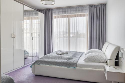 a white bedroom with a bed and a mirror at Apartament francuski in Gdańsk