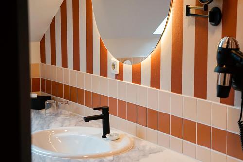 La salle de bains est pourvue d'un lavabo et de carrelage orange et blanc. dans l'établissement Villa Usedom, à Heringsdorf