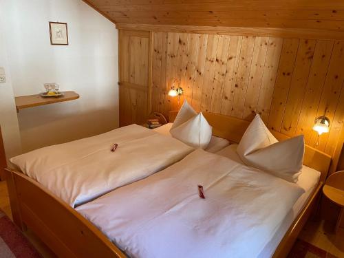 Cama grande en habitación con paredes de madera en Klausmoarhof, en Leisach
