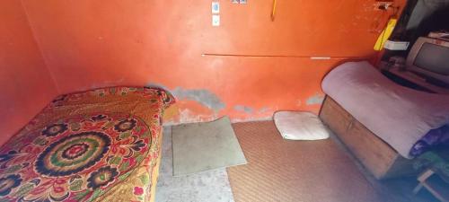 Habitación naranja con cama y cama doble en Sunderdunga Home Stay, en Kapkot