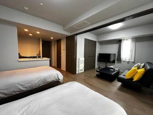 une chambre d'hôtel avec deux lits et un canapé dans l'établissement 5‐2　新築部屋　札幌中心部サービスアパートメントSAPPORO南３条通, à Sapporo