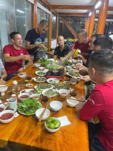 a group of people sitting around a table eating food at Homestay Chân Mây Chiêu Lầu Thi in Hoàng Su Phì