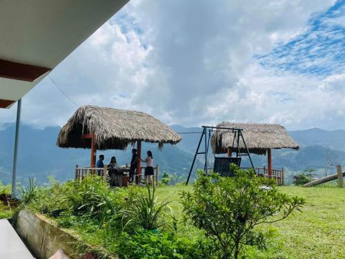 a group of people standing outside of a hut at Homestay Chân Mây Chiêu Lầu Thi in Hoàng Su Phì