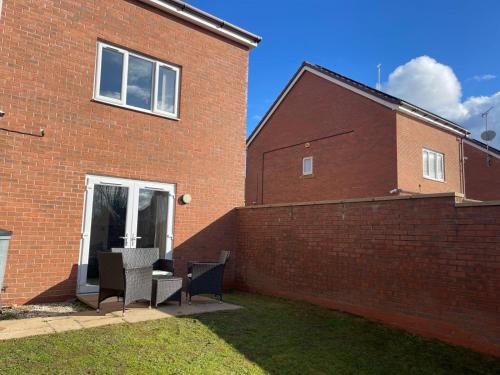 ein Backsteingebäude mit zwei Stühlen und einem Fenster in der Unterkunft 3 Bedroom Affordable Family Detached House - Business Contractors, Midlands Location - Private garden,Free car park,TV- Netflix and Free WiFi in Coventry