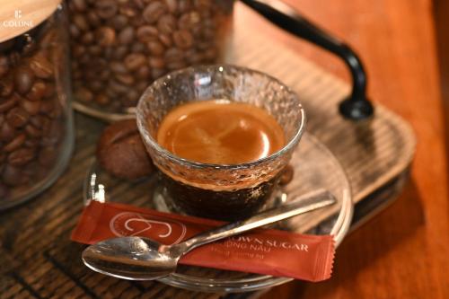 a glass cup of coffee on a glass plate with a spoon at Colline Dalat in Da Lat