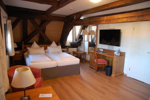 a bedroom with a bed and a desk and a television at Metzgerei Gasthof Romantik Hotel Der Millipp in Beilngries
