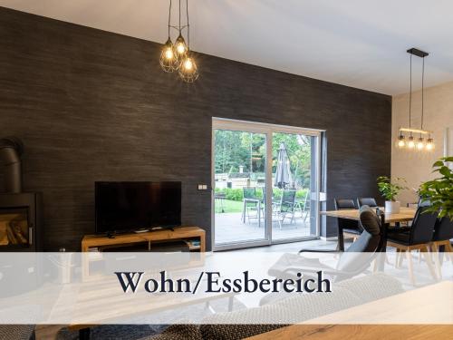a living room with a tv and a dining room at Familienfreundliche Ferienwohnung mit großem Garten, Spielplatz, privatem Badefass & Sauna in Wendisch Rietz