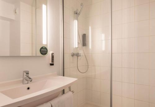 La salle de bains blanche est pourvue d'une douche et d'un lavabo. dans l'établissement B&B HOTEL Marseille La Valentine Porte d'Aubagne, à Marseille