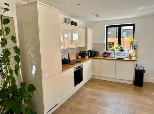 eine Küche mit weißen Schränken und einem Fenster in der Unterkunft Luxurious, spacious, sunny & modern apartment in London