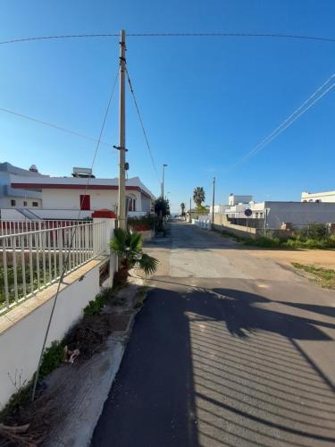 une rue vide avec une clôture blanche et une maison dans l'établissement Trilocale Pescoluse fronte mare, à Marina di Pescoluse