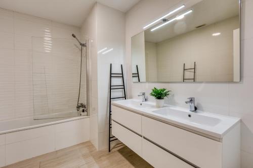 La salle de bains blanche est pourvue d'un lavabo et d'un miroir. dans l'établissement Hanami Arroyo Beach Garden, à Estepona