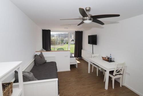 a living room with a couch and a table and a ceiling fan at Aparthotel Peerless Dine in Heidenheim an der Brenz