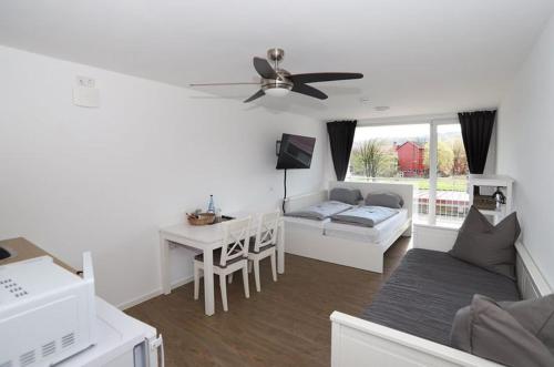 uma sala de estar com uma ventoinha de tecto, um sofá e uma mesa em Aparthotel Peerless Dine em Heidenheim an der Brenz