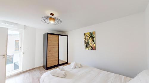 a white bedroom with a bed and a mirror at Le Duplex Forêt Noire in Illkirch-Graffenstaden