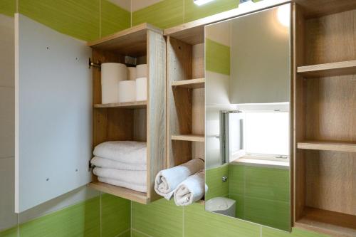 a bathroom with green walls and shelves with towels at Apartman Karolina in Zagreb