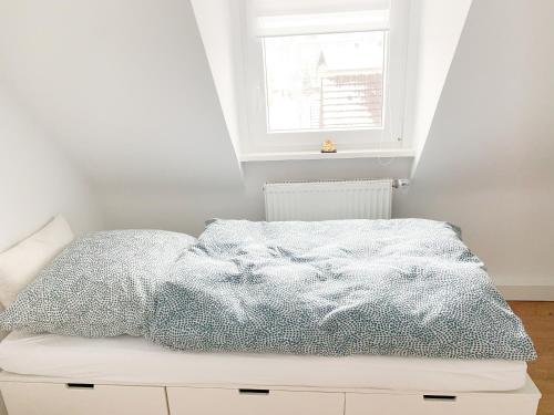 Bett in einem weißen Zimmer mit Fenster in der Unterkunft Spacious house for large groups and families in Würzburg