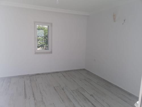 Habitación blanca con ventana y suelo de madera. en reklo en Altındağ