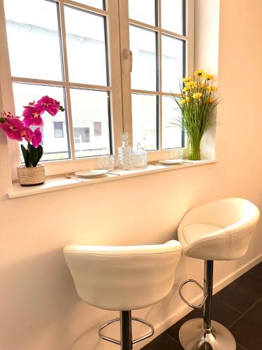 a room with a white chair and flowers in a window at Royal Horses in Overijse