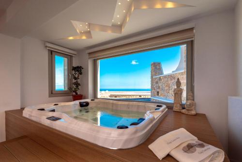 a large bath tub in a room with a large window at Marvel Suite in Imerovigli