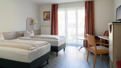 a hotel room with two beds and a chair at Gästehaus Moser in Weil am Rhein