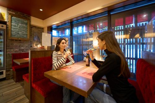 two women sitting at a table in a restaurant drinking wine at Hotel Resol Kyoto Shijo Muromachi in Kyoto