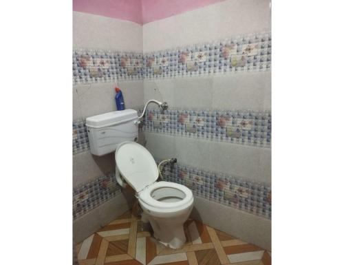 a bathroom with a toilet with mosaic tiles on the walls at Nk Brothers Homestay, Joshimath in Joshīmath