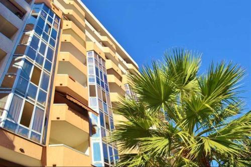 un grand bâtiment avec des palmiers devant dans l'établissement Grand Studio Nice terrasse et piscine, à Nice