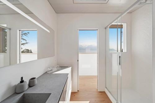 eine weiße Küche mit einem Waschbecken und einer Glastür in der Unterkunft Villa Rose in the center of Montreux by GuestLee in Montreux