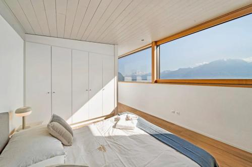 a bedroom with a bed and a large window at Villa Rose in the center of Montreux by GuestLee in Montreux
