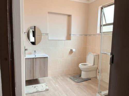 ein Badezimmer mit einem WC, einem Waschbecken und einem Spiegel in der Unterkunft Mapalesa Guest House in Mohales Hoek